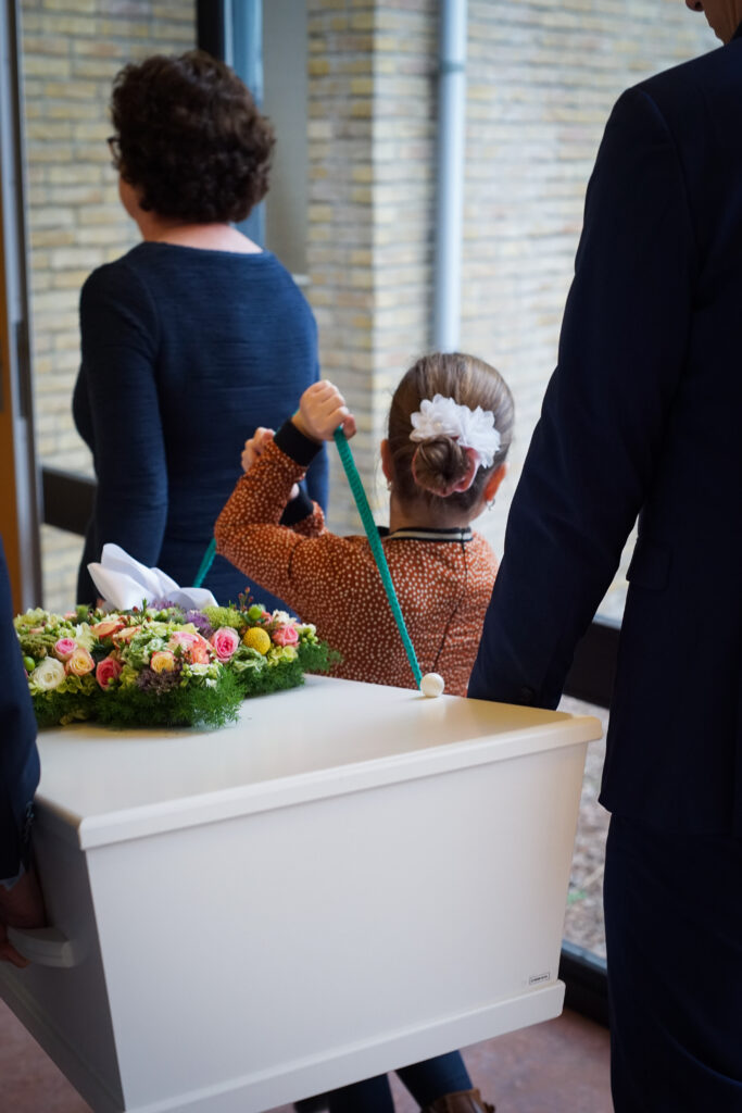 Kinderen helpen de rouwkist dragen